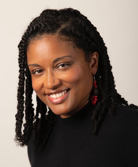 A black woman with shoulder-length braided hair smiling at the camera